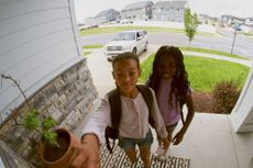 Security camera showing the front door of a home with children coming and going