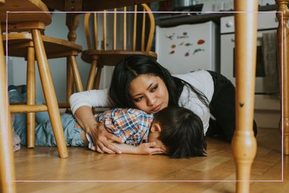 parent on floor comforting a child having a tantrum