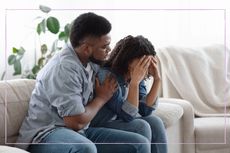 Husband consoling upset wife on the sofa