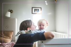 Man comforting toddler in cot