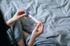 Woman looking at a negative pregnancy test as she wonders, why can't i get pregnant