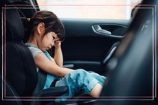 A young girl in a car with her head in her hands