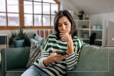 Woman sat on sofa with phone